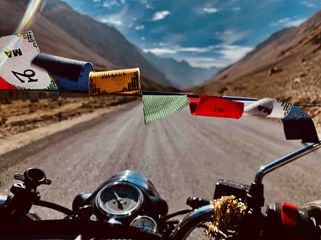 Motorcycle on the World’s Highest Motorable Pass I Buddhist prayer flags on a Bike on its Journey to the mystical Himalayas