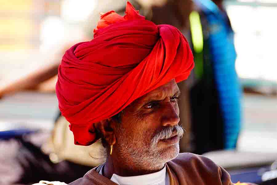 A portrait view of a man of Rajasthan, clad in a red turban, white beard, wearing earring I Beauty of Indian Villages on Bike