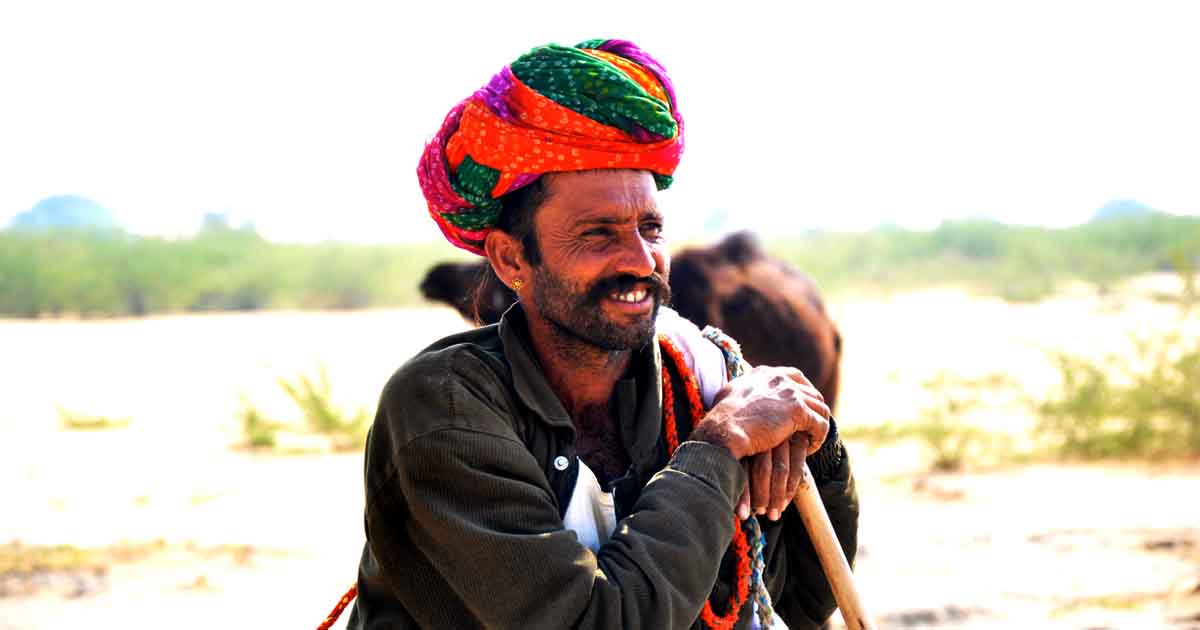 An Image of a Traditional Rajasthani man wearing angrakha & bright colored turban & in ethnic jewelry I Cultural Tourism